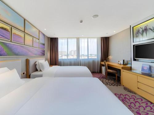 a hotel room with two beds and a desk and a tv at Lavande Hotel Foshan Shunde Shunlian Plaza Jinlong Metro Station in Shunde