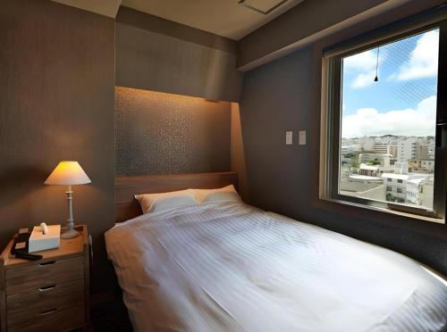 a bedroom with a large bed and a window at Ryuka Hotel Naha in Asato