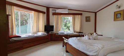 a bedroom with two beds and a tv and two windows at Sunset Beach Resort in Candolim