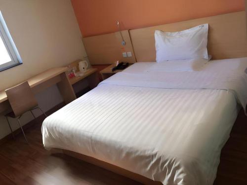 a bedroom with a large white bed and a desk at 7 Days Inn West Gate of Taiyuan University of Technology in Taiyuan