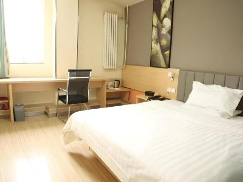 a bedroom with a white bed and a chair at 7 Days Inn West Gate of Taiyuan University of Technology in Taiyuan