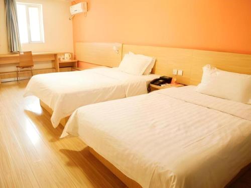 two beds in a hotel room with white sheets at 7 Days Inn West Gate of Taiyuan University of Technology in Taiyuan