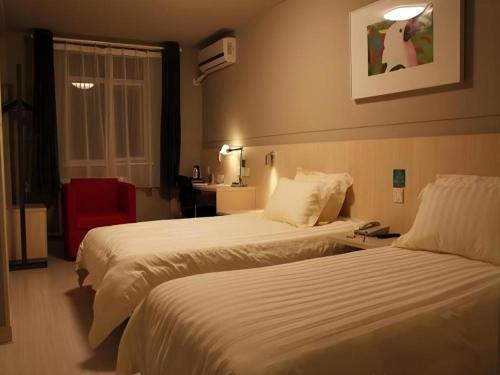 a hotel room with two beds and a red chair at Jinjiang Inn Yantai Fushan District Fuhai Road in Yantai