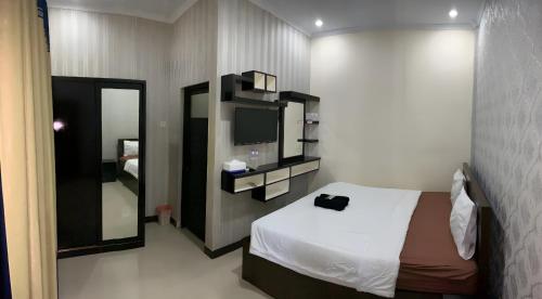 a bedroom with a bed and a mirror and a television at Prime Adisucipto Hotel in Kalasan