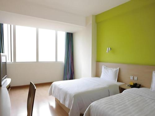 a hotel room with two beds and a green wall at 7 Days Inn Guangzhou Zoo Huanghuagang Metro Station in Guangzhou