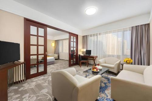 a living room with a couch and chairs and a television at Shantou Golden Gulf Hotel in Shantou