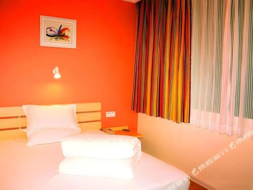 a bedroom with a bed with an orange wall at 7 Days Inn Guangzhou Zoo Huanghuagang Metro Station in Guangzhou