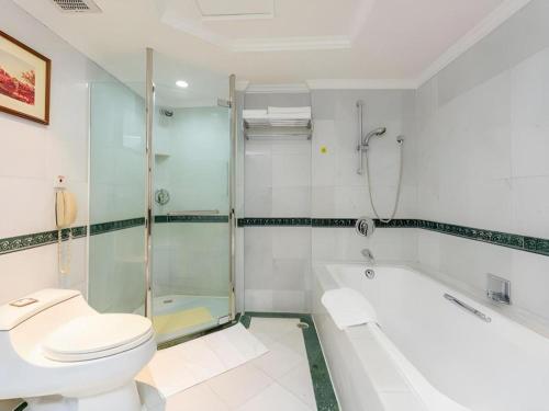 a bathroom with a toilet and a tub and a sink at Shantou Golden Gulf Hotel in Shantou
