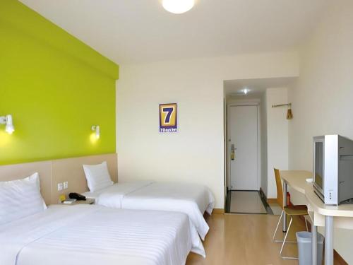 two beds in a room with a green wall at 7 Days Inn Guangzhou Zoo Huanghuagang Metro Station in Guangzhou