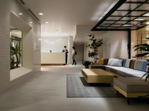 a living room with a couch and a person in the background at Hotel Edit Yokohama in Yokohama