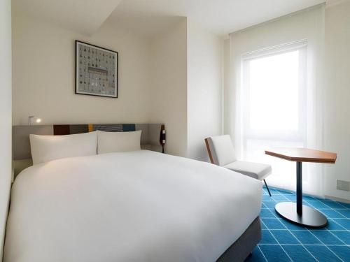 a hotel room with a bed and a desk and a window at Hotel Edit Yokohama in Yokohama