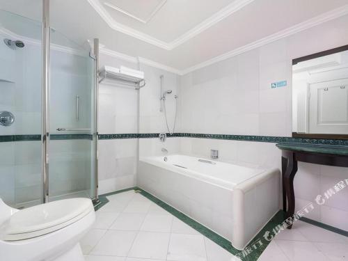 a white bathroom with a toilet and a sink at Shantou Golden Gulf Hotel in Shantou