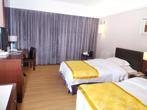 a hotel room with two beds and a television at Shantou Golden Gulf Hotel in Shantou