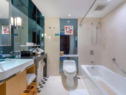 a bathroom with a tub and a toilet and a sink at Shantou Golden Gulf Hotel in Shantou