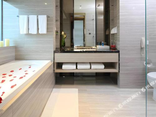 a bathroom with a tub and a sink and a toilet at Huafa Executive Apartment Hotel Zhuhai in Zhuhai