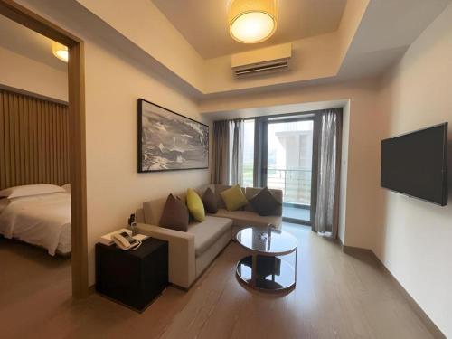a living room with a couch and a tv and a bed at Huafa Executive Apartment Hotel Zhuhai in Zhuhai
