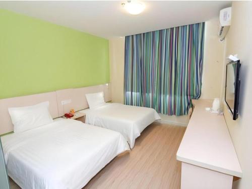 a hotel room with two beds and a window at 7 Days Inn Changchun Zhengyang Street Changchun Park Branch in Changchun