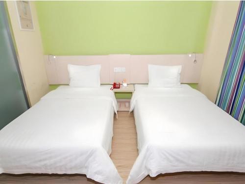 two beds in a small room with white sheets at 7 Days Inn Changchun Zhengyang Street Changchun Park Branch in Changchun