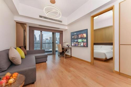 a living room with a couch and a bed and a bedroom at Huafa Executive Apartment Hotel Zhuhai in Zhuhai