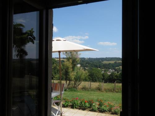 a view from a window of a patio with an umbrella at Cherveix in Solignac