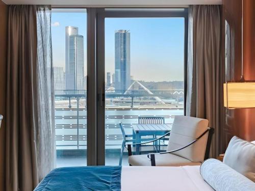 a room with a bed and a window with a table and chairs at Huafa Executive Apartment Hotel Zhuhai in Zhuhai