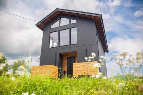 a small black house in a field of grass at White Sierra Chalet in Hakuba