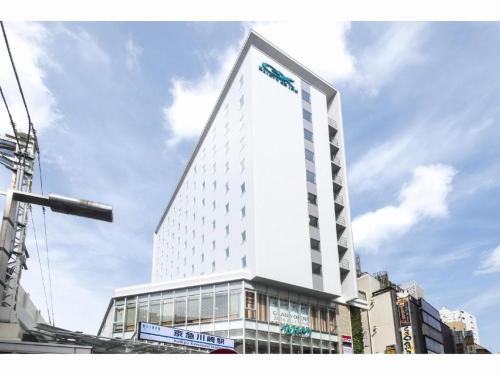 a tall white building with a sign on it at KEIKYU EX INN Keikyu Kawasaki-Station in Kawasaki