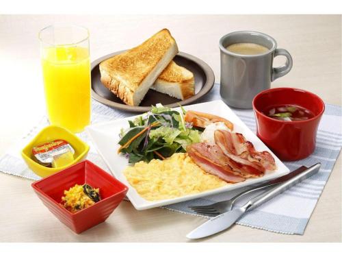 a table with a plate of breakfast food and a cup of orange juice at KEIKYU EX INN Keikyu Kawasaki-Station in Kawasaki