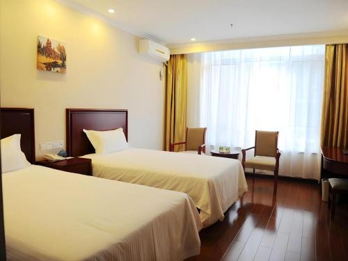 a hotel room with two beds and a window at GreenTree Inn Qinhuangdao Peace Avenue Express Hotel in Qinhuangdao