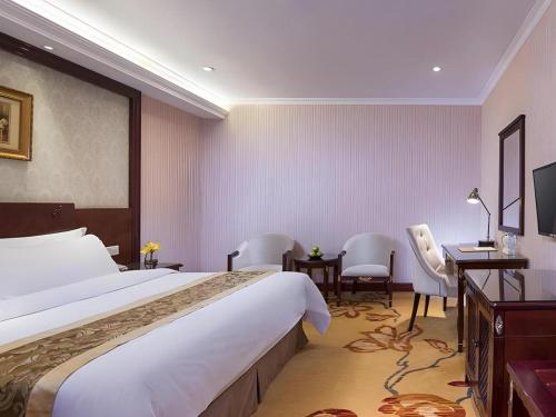 a hotel room with a large bed and a desk at Vienna 3 Best Hotel Dongguan Fenggang Yongsheng Street in Tiantangwei