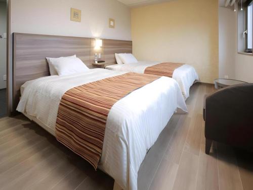 a hotel room with two beds and a chair at Hotel Sunoak Kashiwanoha in Kashiwa