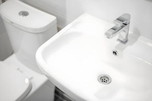 a bathroom with a white sink and a toilet at Meesuk ChiangRai Hotel in Chiang Rai
