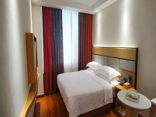 a hotel room with a bed and a television at GreenTree Inn Geermu Walking Street Business Hotel in Golmud