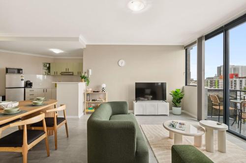 a living room with a green couch and a table at Spacious Apartment in East Perth - Close to OPTUS Stadium, CBD, WACA in Perth
