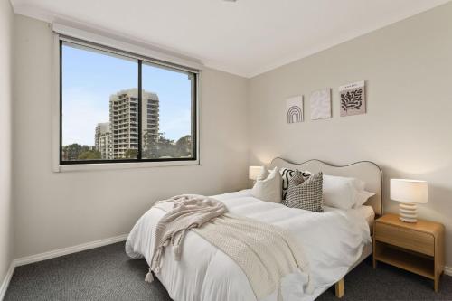 a white bedroom with a bed and a window at Spacious Apartment in East Perth - Close to OPTUS Stadium, CBD, WACA in Perth