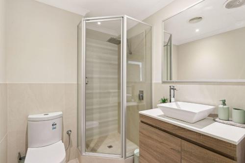 a bathroom with a shower and a toilet and a sink at Spacious Apartment in East Perth - Close to OPTUS Stadium, CBD, WACA in Perth