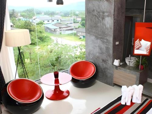 two red chairs sitting on a table in front of a window at The B Ranong Trend Hotel in Ranong