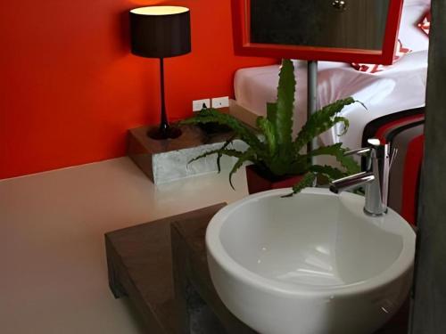 a bathroom with a sink and a plant next to a bed at The B Ranong Trend Hotel in Ranong