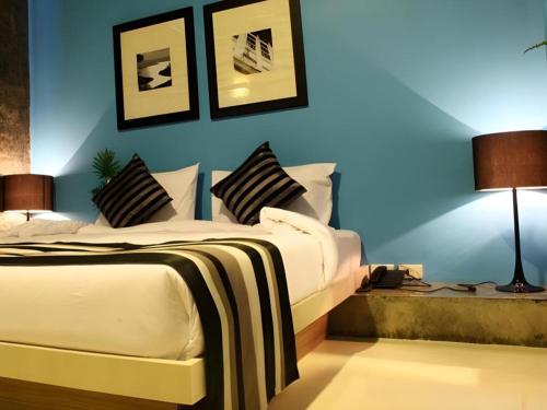 a bedroom with a bed and a blue wall at The B Ranong Trend Hotel in Ranong