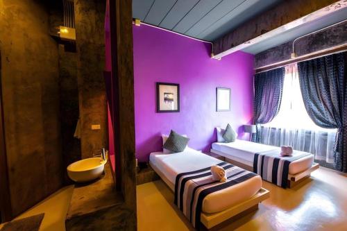 a purple room with two beds and a tub at The B Ranong Trend Hotel in Ranong