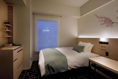 a small bedroom with a bed and a window at Hotel Yaenomidori Tokyo in Tokyo