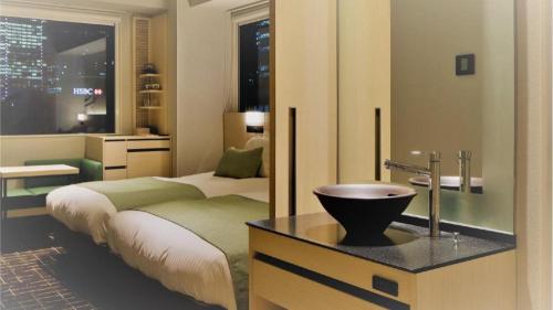 a bedroom with a bed and a bathroom with a sink at Hotel Yaenomidori Tokyo in Tokyo