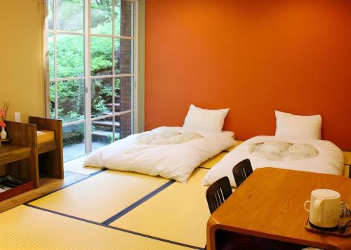 two beds in a room with a table and a window at Fuji Shoei kaikan in Fuji