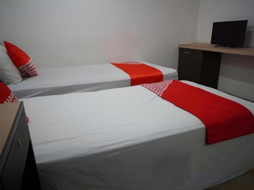 two beds with red and white sheets in a room at OYO 92863 Hotel Blessing in Surabaya