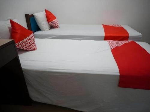 a bedroom with two beds with red and white pillows at OYO 92863 Hotel Blessing in Surabaya