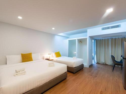 a hotel room with two beds and a desk at Hotel Holm Bangkok in Bangkok