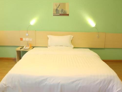 a large white bed in a room with two lights at 7 Days Inn Guangrao Bus Station in Dongying