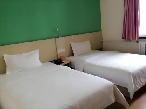 two beds sitting next to each other in a room at 7 Days Inn Guangrao Bus Station in Dongying