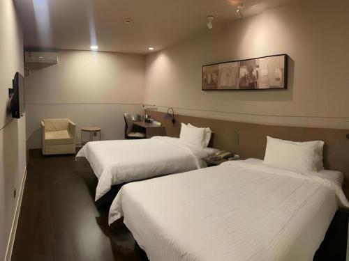 a hotel room with two beds and a desk at Jinjiang Inn Select Shanghai Fengxian Baolong Square North Yunhe Road in Shanghai