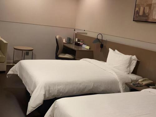 a hotel room with two beds and a desk at Jinjiang Inn Select Shanghai Fengxian Baolong Square North Yunhe Road in Shanghai